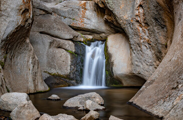 Secret hidden waterfall in a narrow rocky canyon with a long exposure capture. its a secret to...
