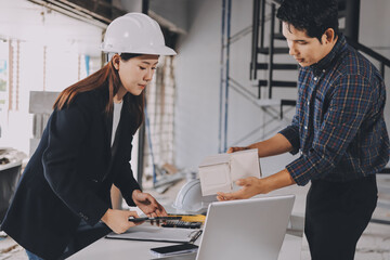 Construction manager and engineer dressed in orange work vests and hard helmets explore...