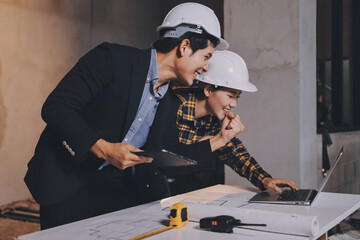 Construction manager and engineer dressed in orange work vests and hard helmets explore...