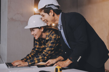 Construction manager and engineer dressed in orange work vests and hard helmets explore...