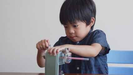 鉛筆削りを回す5歳の男の子