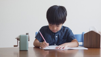 ひらがなのを書く練習をする5歳の男の子