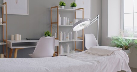 Cosmetology spa treatment room with a neatly made massage table, magnifying lamp, dermatology room. Professional massage setup for relaxing wellness treatments.