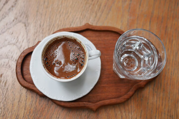 Enjoying coffee with a glass of water on a wooden tray