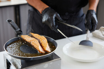 chef cooking salmon steaks in the kitchen