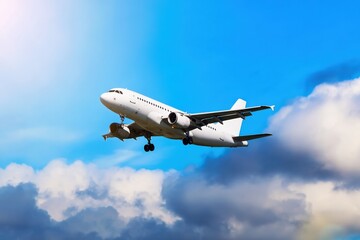 Fototapeta premium White passenger airplane soaring high above the clouds, gliding effortlessly on a beautiful sunny day, capturing the essence of travel and freedom