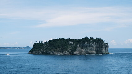 A serene seascape featuring Jeju island with a lighthouse in the distance, under a sky filled with clouds. 