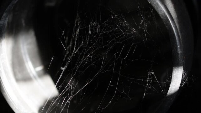 Glistening strands of a spiderweb in utter darkness.