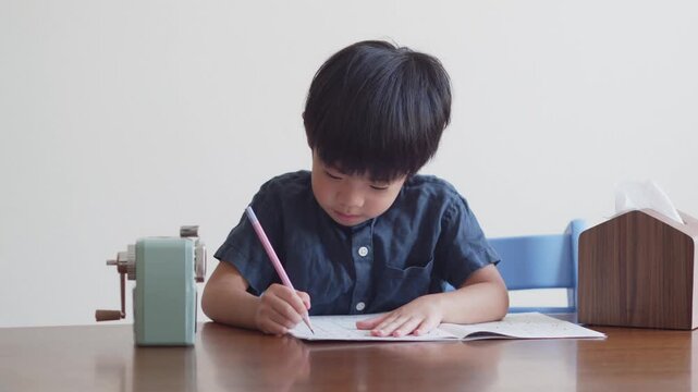 ひらがなのを書く練習をする5歳の男の子	