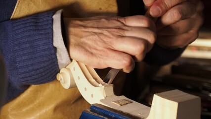 Skilled woodworker carefully carving hardwood plank, clamped within workshop vise, using specialized gouge under soft lamplight, revealing intricate luthier craftsmanship