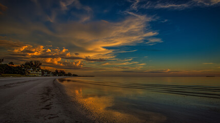 sand. A breathtaking tropical beach sunset with vibrant clouds and golden reflections on the wet sand. inspiring travel planning, travel magazines, designed for outdoor magazines and nature guides.