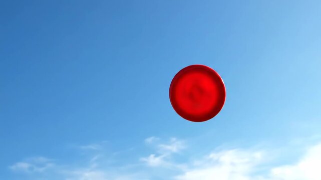 Red frisbee flying high in the bright blue sky.