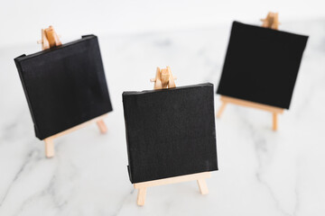 black canvases on miniature easels on white marble, mockup with copy space, shallow dof