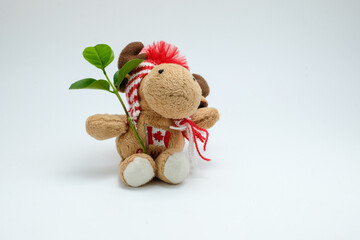 Cute moose plush toy wearing winter accessories holding a small green plant on clean white background. Perfect for illustrating eco-friendly lifestyle, holiday gifts, education, and nature concepts
