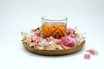 Glass of herbal drink placed on a wooden plate surrounded by shallot and garlic peels on a wooden plate. Suitable for traditional medicine, herbal remedy, lifestyle, and natural health care, wellness