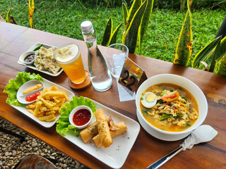 West food on the table. Fried fries, boiled noodles, and fried food in the morning with lemon tea and mineral water
