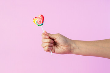 Sweets, two lollipops in hand, on pink background