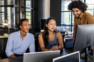 Collaborating in modern office, diverse team discussing project on computer screen