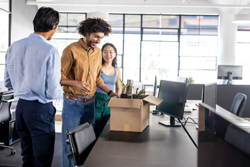 Colleagues unpacking welcome gift box in modern office, smiling and chatting