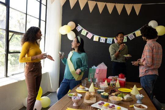 Colleagues enjoying baby shower celebration at office with snacks and decorations