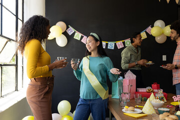 Celebrating baby shower, diverse friends enjoying conversation and snacks at party