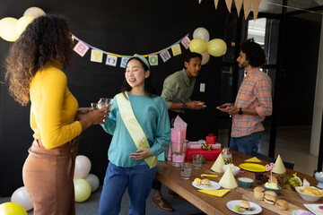 Celebrating baby shower, diverse friends enjoying food and conversation at home
