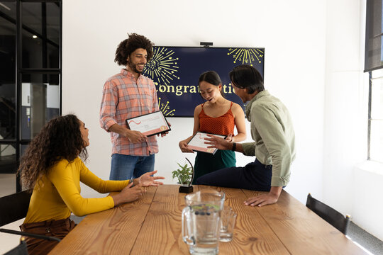 Colleagues celebrating achievements with certificates in modern office meeting room