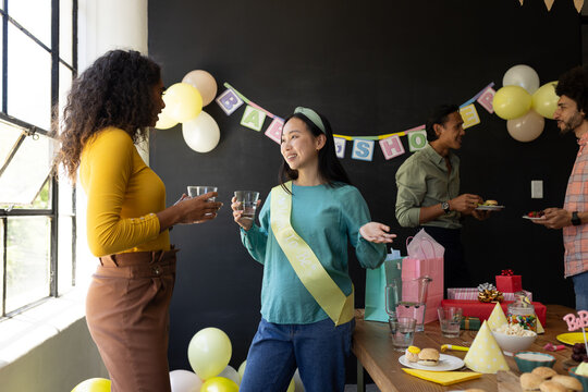 Celebrating baby shower, diverse friends enjoying conversation and snacks at party - Powered by Adobe