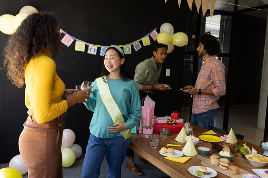 Celebrating baby shower, diverse friends enjoying food and conversation at home