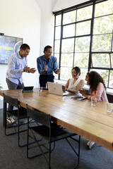 In office, diverse team collaborating on laptop, enthusiastically sharing ideas