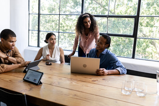 Diverse business team collaborating with laptops and tablets in modern office