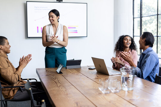 In modern office, business team applauding colleague presenting digital marketing strategy