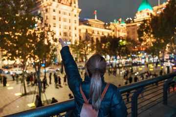 Obraz premium woman traveler visiting in Shanghai, China. Happy Female Tourist sightseeing Shanghai view in The Bund of Shanghai at night. landmark and popular for tourism attractions. Travel and Vacation concept
