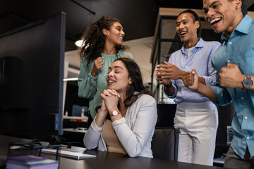 Diverse business team celebrating success at office, smiling and clapping together