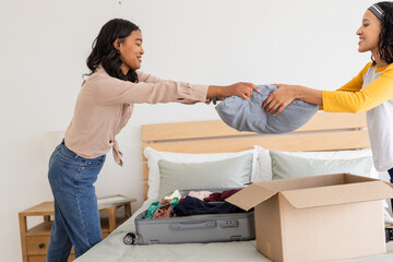 Mother and daughter packing suitcase together, preparing for family trip at home