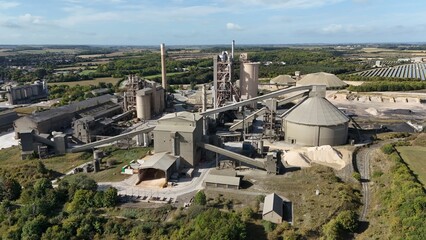 Aerial drone view of heavy industrial cement factory, manufacturing production with smoke stacks and warehouses, aggregates and processing, England UK