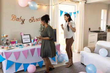 Decorating for baby shower at home, African American woman and friend looking excited
