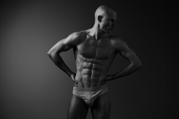 Fototapeta premium Strong man posing in black and white, showcasing athletic physique and confidence, highlighting muscular definition and artistry in form.