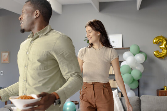 African American man and woman celebrating birthday at home with balloons and snacks