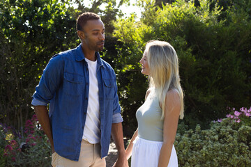 Couple enjoying romantic moment in garden, holding hands and smiling warmly