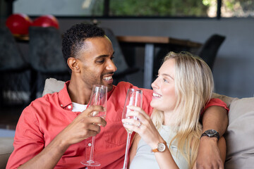Couple celebrating at home, smiling and toasting with champagne glasses
