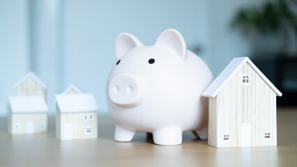 Piggy bank with miniature houses highlighting real estate investment, property ownership, and financial savings for home security.
