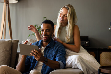Couple at home enjoying video call on tablet, smiling and relaxing on couch