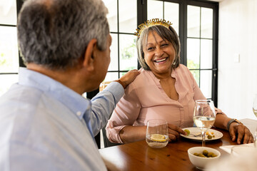 Celebrating birthday, African American woman smiling with friend at dining table
