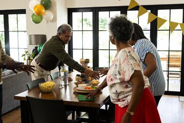 Family gathering around dining table sharing snacks and enjoying festive celebration