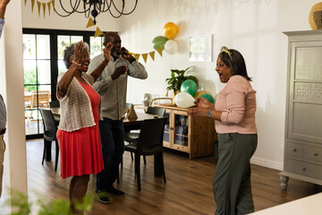 Joyful seniors dancing and celebrating at home with balloons and decorations
