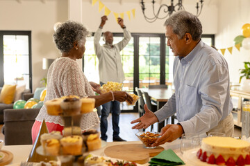 Senior couple enjoying festive gathering with snacks and decorations at home