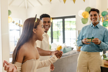 Friends celebrating birthday at home, laughing and exchanging gifts with joy