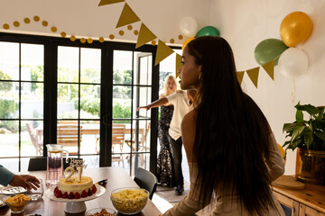 Young woman celebrating 21st birthday blowing out candles on cake at home