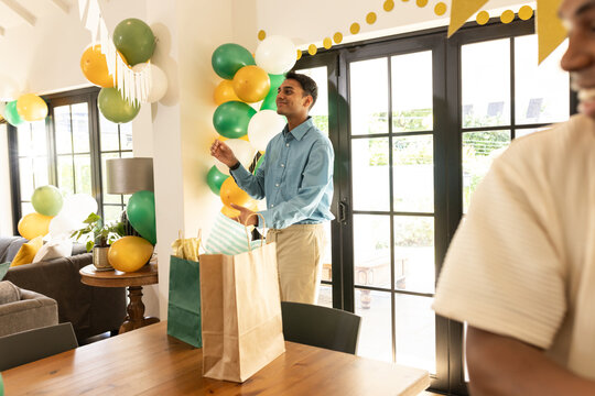 Man decorating living room with balloons and banners for festive celebration - Powered by Adobe